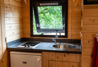 Compact kitchenette with stovetop, sink, and open window inside a mobile home at Holiday Park Ardinam 1, Belgium.