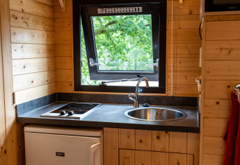 Piccola cucina con piano cottura, lavello e finestra aperta in una casa mobile a Holiday Park Ardinam 1, Belgio.