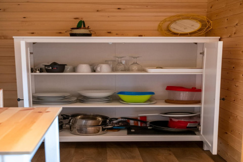 Küchenschrank im Mobilheim Holiday Park Ardinam 1 in Belgien, gefüllt mit Geschirr und Töpfen.