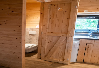 Innenaufnahme eines Mobilheims Holiday Park Ardinam 1 in Belgien mit Holzwänden, Küche und Bad.