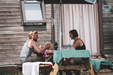 Een stel zit aan een tafel buiten een stacaravan in Holiday Park Ardinam 1, België, genietend van hun tijd samen.