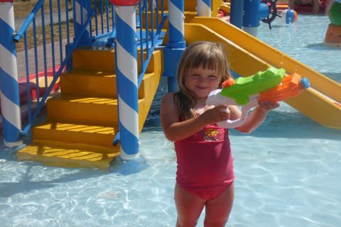 Mädchen im Badeanzug spielt mit einer Wasserpistole im Wasserpark Holiday Park Ardinam, Belgien.