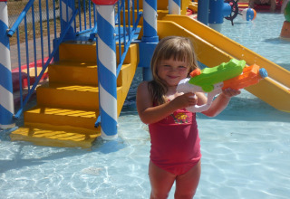 Bambina in costume da bagno con pistola ad acqua nell'area giochi d'acqua di Holiday Park Ardinam, Belgio.