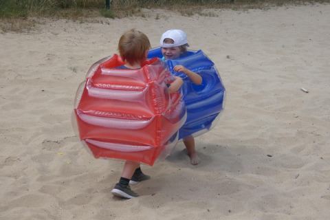 Zwei Kinder spielen in aufblasbaren Sumoanzügen im Sand im Holiday Park Ardinam 1 in Belgien.