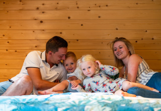 Gezin relaxt samen in een stacaravan bij Holiday Park Ardinam 1 in België, met houten wand op de achtergrond.
