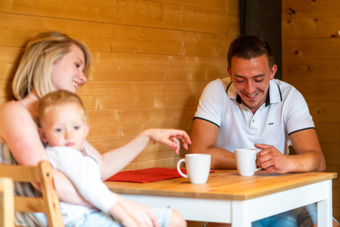 Una famiglia sorseggia caffè insieme al tavolo nel mobil home Holiday Park Ardinam 1 in Belgio.