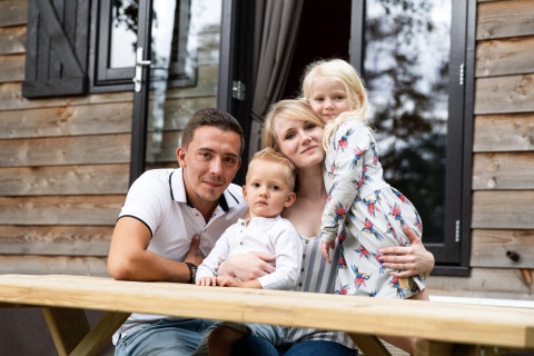 Una famiglia seduta insieme davanti a una casa mobile a Holiday Park Ardinam 1 in Belgio, che si gode l’aria aperta.