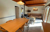 Area soggiorno e pranzo accogliente nel chalet LIJSTERNEST, Belgio, con soffitto in legno e tavolo da pranzo.