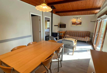 Area soggiorno e pranzo accogliente nel chalet LIJSTERNEST, Belgio, con soffitto in legno e tavolo da pranzo.