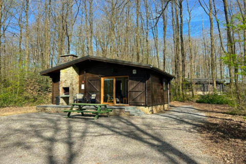 Chalet « LIJSTERNEST » en Belgique au cœur de la forêt, avec table de pique-nique et terrasse ensoleillée.