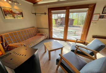 Wohnzimmer im Chalet LIJSTERNEST in Belgien mit großen Fenstern, Sofa und Sesseln.