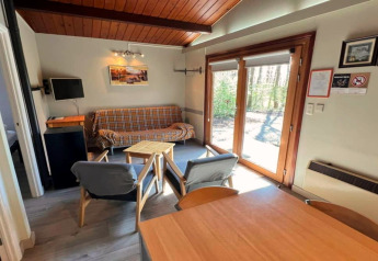 Wohnzimmer im Chalet LIJSTERNEST in Belgien, mit Holzbalkendecke, Fenster, Sofa und Sesseln.