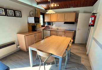 Moderne Chalet-Küche im LIJSTERNEST Belgien mit Esstisch, Stühlen und Küchenschränken bei Tageslicht.