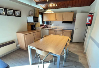 Cuisine moderne de chalet au LIJSTERNEST Belgique avec table en bois, chaises, meubles et puits de lumière.