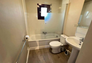 Salle de bain moderne du chalet LIJSTERNEST en Belgique, avec baignoire, toilettes et lavabo.