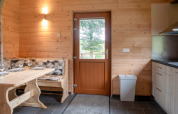 Interior of Rogery 64 chalet in Belgium featuring wood walls, dining table, and door with outside view.