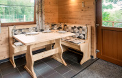 Cozy wooden dining nook with set table for four, in Rogery 64 chalet, Belgium, natural light in view.