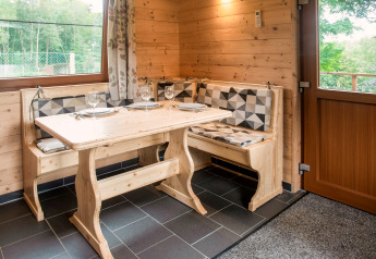 Cozy wooden dining nook with set table for four, in Rogery 64 chalet, Belgium, natural light in view.