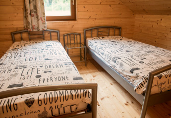Two single beds with text-patterned bedding in a wood-paneled room at chalet Rogery 64 in Belgium.
