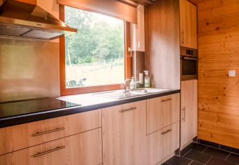 Modern kitchen interior at Rogery 64 chalet in Belgium, featuring wood cabinets and large window.