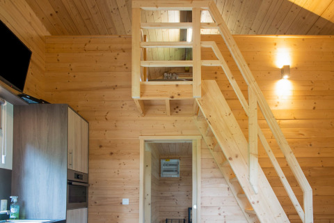 Interieur van chalet Rogery 64 in België met houten vide, trap en een moderne keukenhoek.