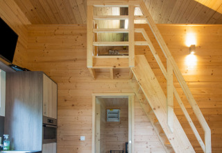 Interieur van chalet Rogery 64 in België met houten vide, trap en een moderne keukenhoek.