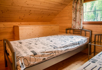 Wood-paneled bedroom with single beds and a window in Chalet Rogery 64, Belgium, taken during daytime.