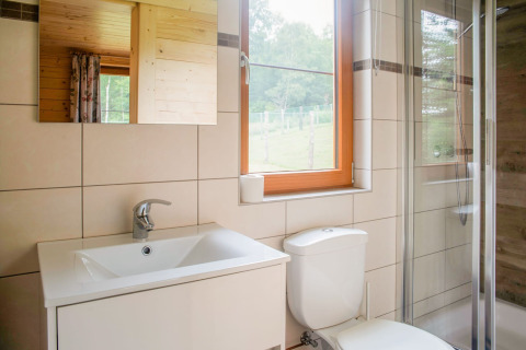 Lichte, moderne badkamer in chalet Rogery 64 in België met raam, douche, wastafel en toilet.