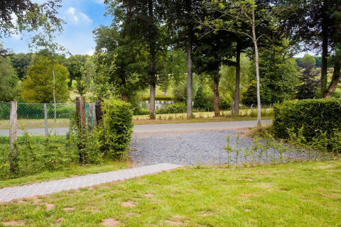 Uitzicht vanaf chalet Rogery 64 in België met grasveld, weg, bomen en een vijver op de achtergrond.