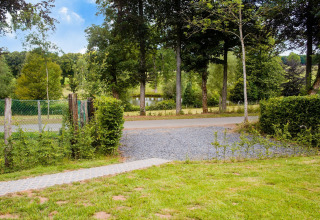 Uitzicht vanaf chalet Rogery 64 in België met grasveld, weg, bomen en een vijver op de achtergrond.