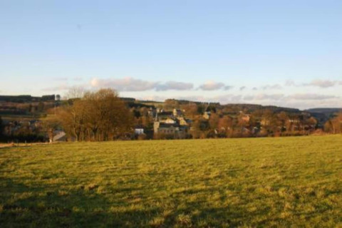 Uitzicht vanaf chalet Rogery 64 in België met een groen veld vooraan en een dorp in de verte.
