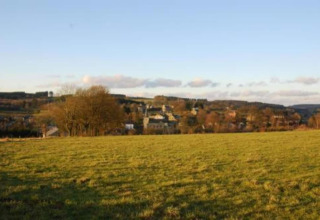 Uitzicht vanaf chalet Rogery 64 in België met een groen veld vooraan en een dorp in de verte.