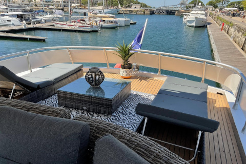 Luxury seating area on Yacht Aquamarina with loungers and stylish decor, docked in a vibrant marina.