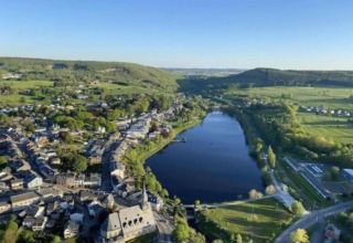 Luchtfoto van meer, dorp en groene velden gemaakt vanaf chalet Rogery 64 in België op een zonnige dag.