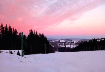 Sunset over a snowy landscape with forests near chalet Rogery 64 in Belgium, featuring a pink sky.