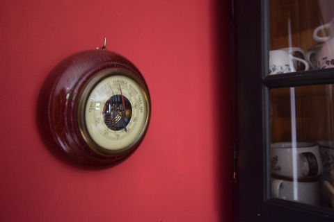 Et barometer med træramme hænger på en rød væg i et chalet ved navn 'Flons et Roulotte' i Belgien.