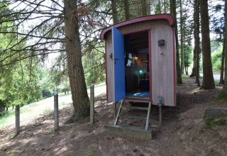 Et charmerende lille chalet ved navn 'Flons et Roulotte' i en skovklædt del af Belgien med åben dør.