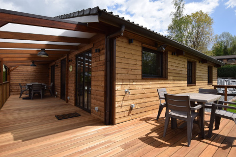 Houten terras met moderne stoelen en tafels bij lodge Famenne, midden in het groen in België.