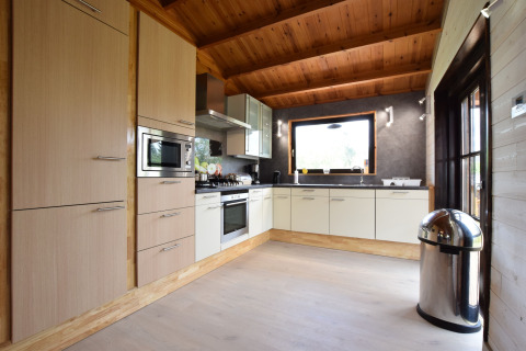 Moderne keuken in lodge Famenne in België met houten plafond, groot raam en ingebouwde toestellen.