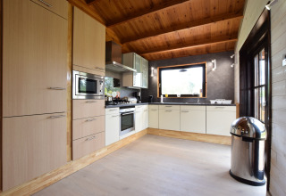 Moderne keuken in lodge Famenne in België met houten plafond, groot raam en ingebouwde toestellen.
