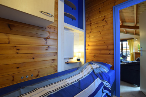 Knusse slaapkamer met houten wanden en blauwe lakens in lodge Famenne, België.