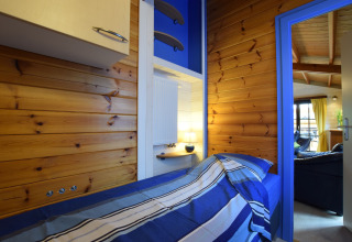 Knusse slaapkamer met houten wanden en blauwe lakens in lodge Famenne, België.
