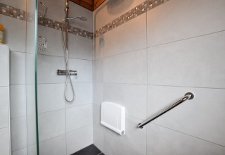 Moderne douche met opklapbaar zitje, handdouche en steunbeugel in de lodge Famenne te België.