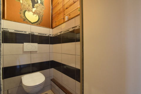 Moderne toiletruimte met zwevend toilet en kunstwerk bij Famenne-lodge in België, betegelde muren.