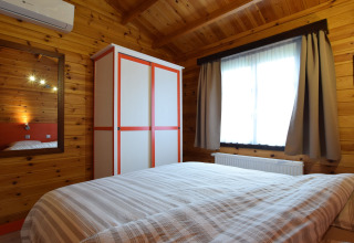 Knusse slaapkamer met houten muren, kast en raam in de lodge «Famenne» in België.