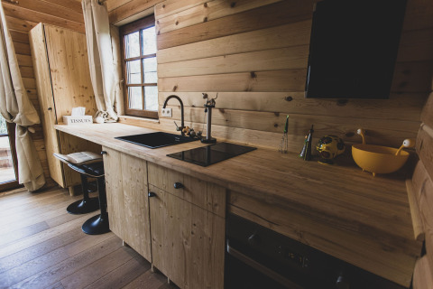 Modern wooden kitchen with large window in Bird Nest tree house, Belgium, featuring cozy, rustic decor.