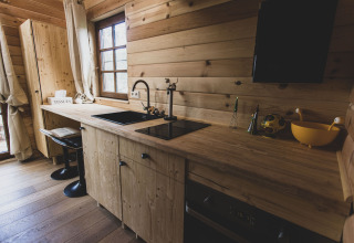 Cucina moderna in legno con ampia finestra nella casa sull'albero Bird Nest, Belgio, atmosfera accogliente.