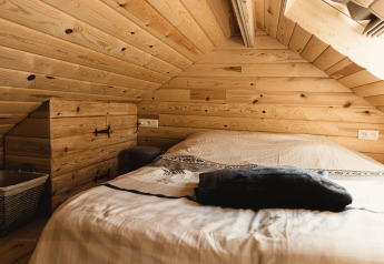 Gemütliches Schlafzimmer mit Holzvertäfelung im „Bird Nest“ Baumhaus in Belgien.