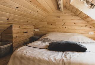 Camera accogliente con soffitto e pareti in legno nella casa sull’albero «Bird Nest» in Belgio.