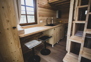 Cucina moderna in una casa sull’albero Bird Nest con sgabelli, legno e scala in Belgio.